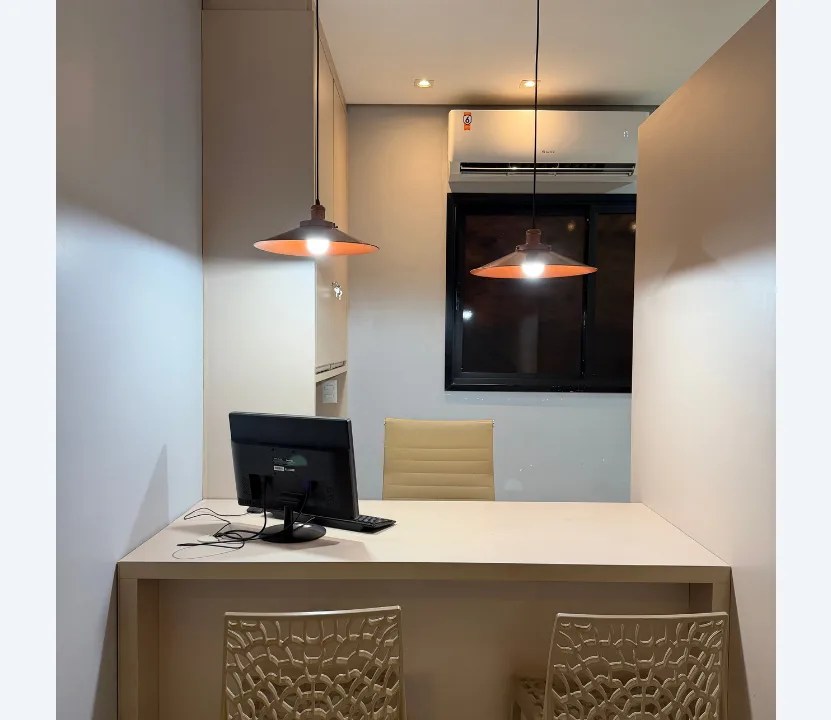 Consultório do Edifício Saúde com mesa de atendimento, cadeiras e luminárias
